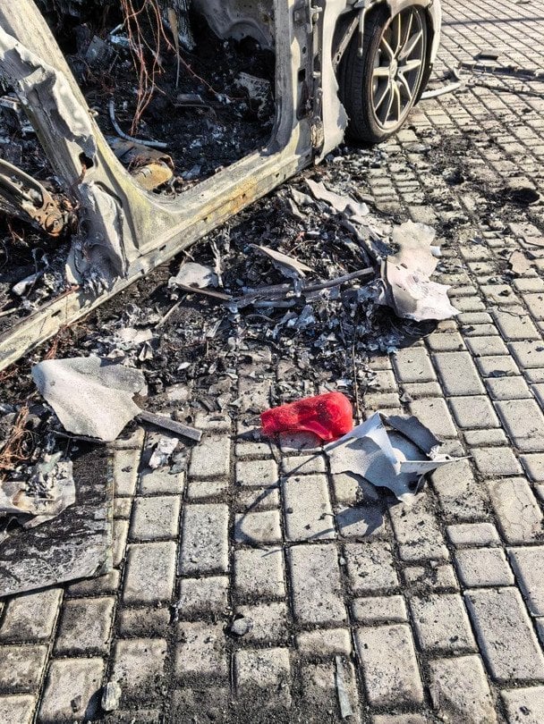 Уламки згорілого авто та попіл на бруківці після вибуху